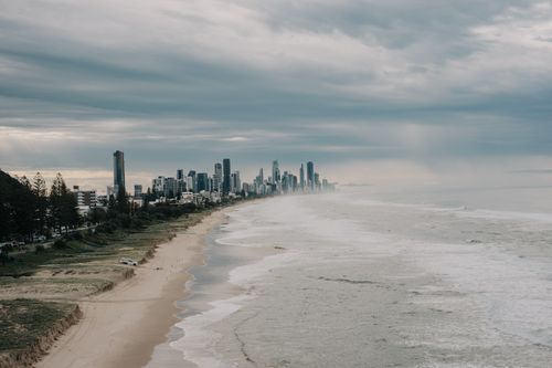 Free A dramatic view of Gold Coast, Australia, with a cloudy sky and waves crashing on the beach. Stock Photo