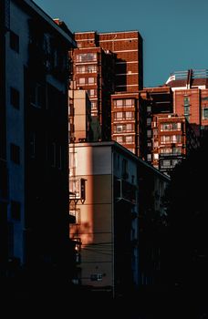 Dramatic shadows and warm tones highlight urban architecture at dusk.