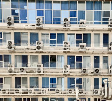 Close-up of modern building exterior with air conditioners on every floor.