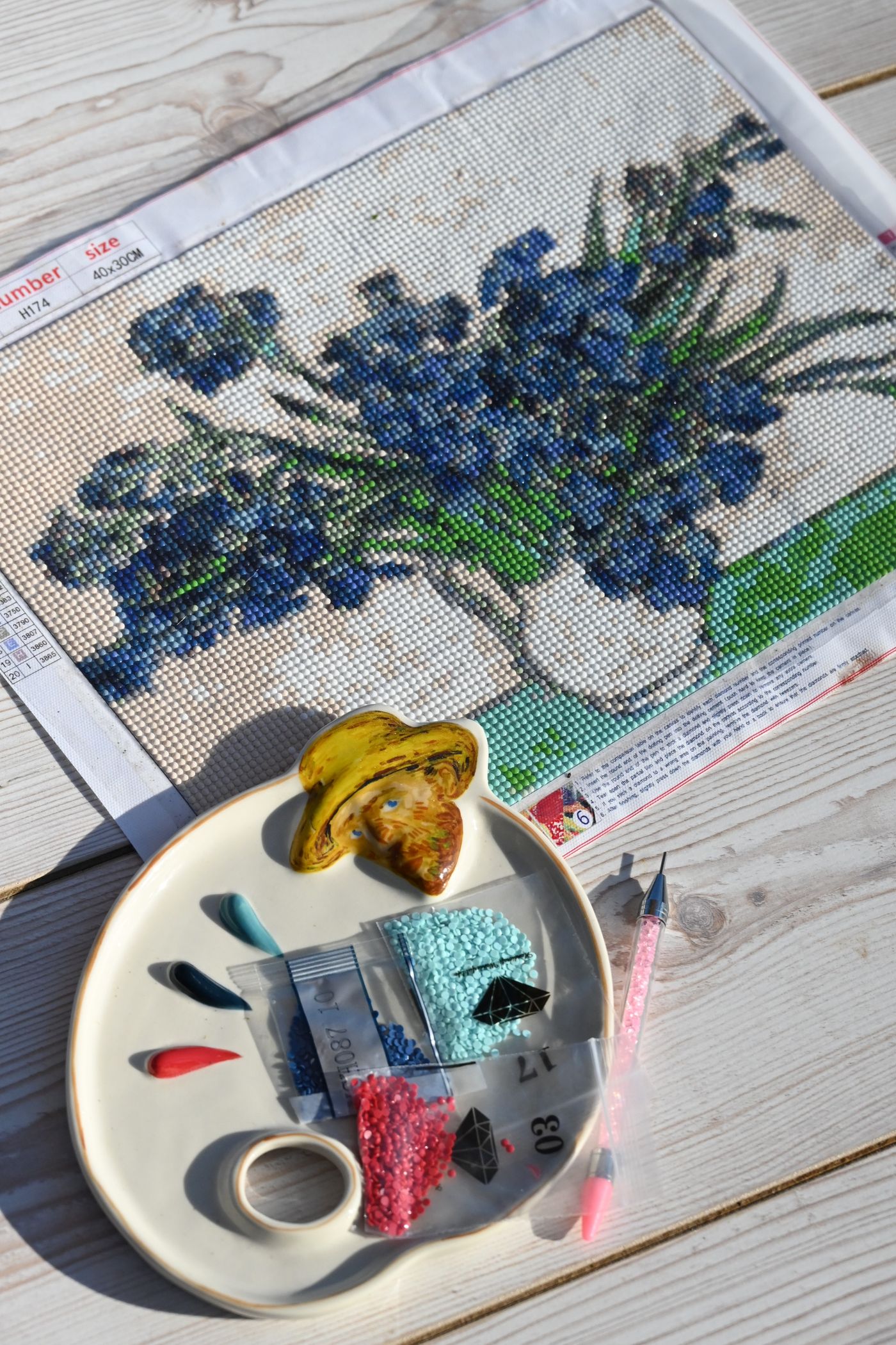 Diamond painting kit laid out with canvas, tray, applicator pen and colourful resin diamonds