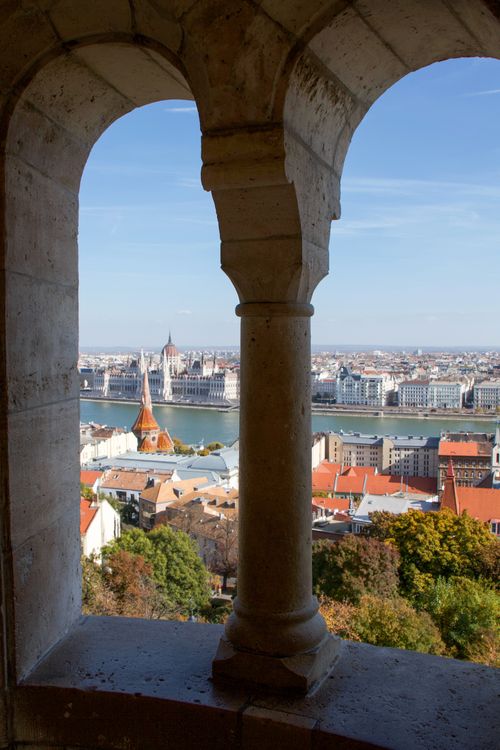 Free Scenic view of Budapest Parliament through Fisherman's Bastion arches on a sunny day. Stock Photo