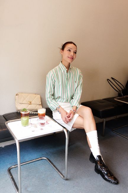 A stylish woman in a striped shirt enjoys drinks at a café indoors.