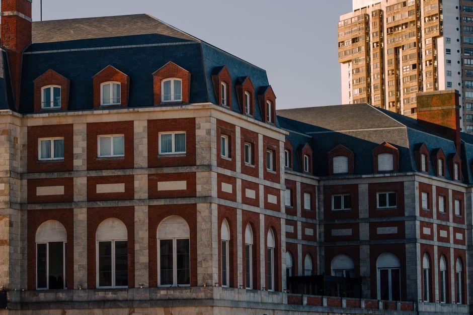 Primer plano de un edificio histórico en Mar del Plata, que muestra un diseño arquitectónico clásico con ladrillo rojo y ventanas arqueadas.