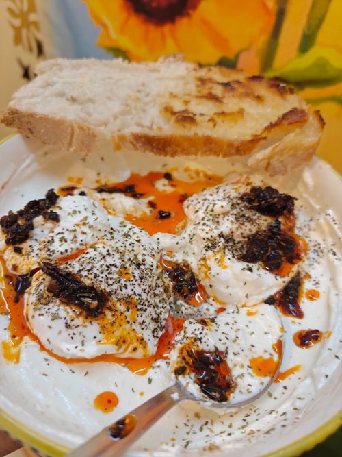 Free Delicious Turkish poached eggs served with yogurt, chili oil, and fresh bread. Stock Photo