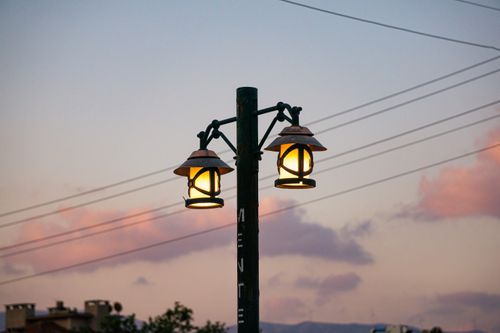 Free A street lamp glowing at dusk with pastel sky and clouds in the background. Stock Photo