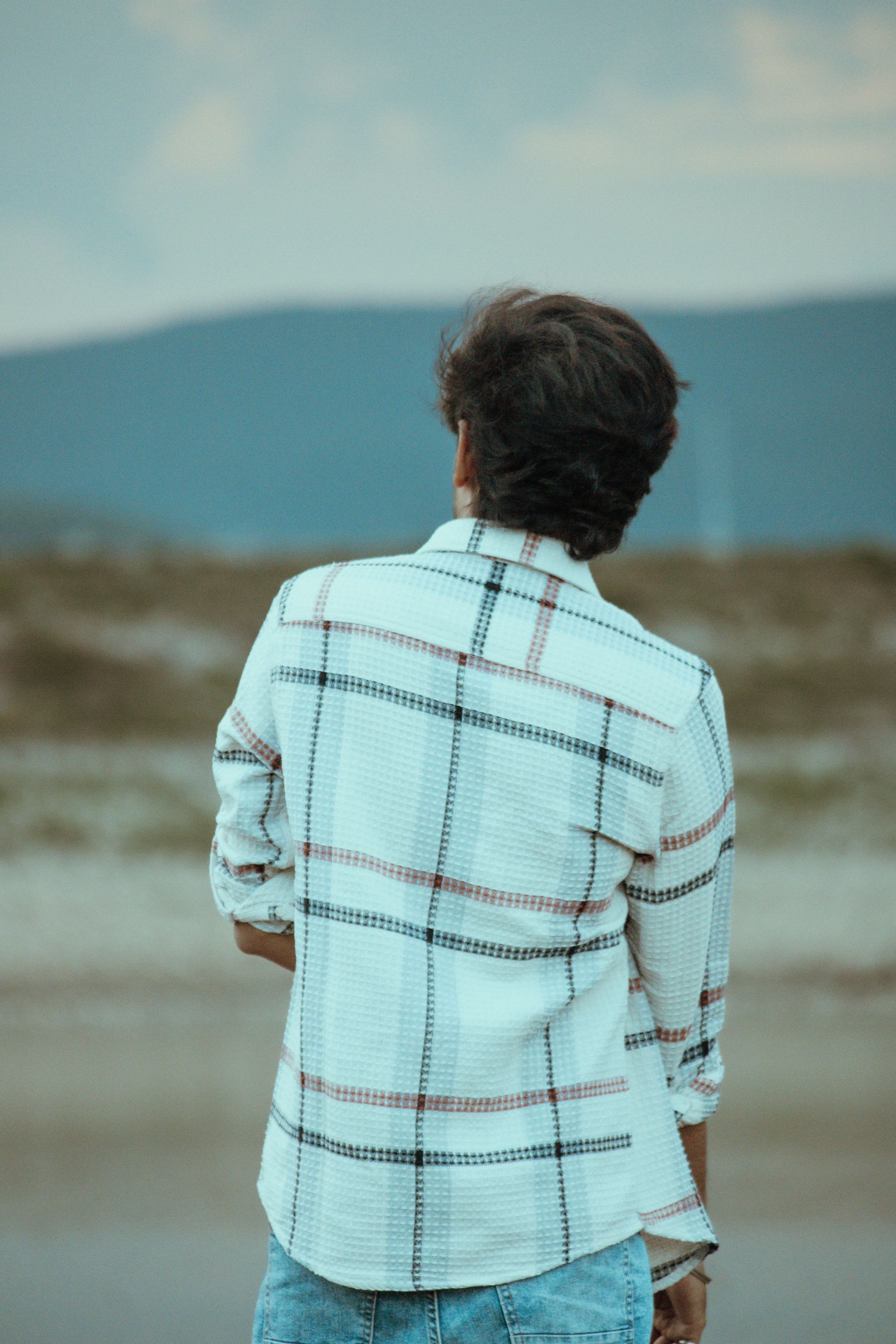 A person stands contemplatively outdoors, back towards camera, in Salem, TN, India.