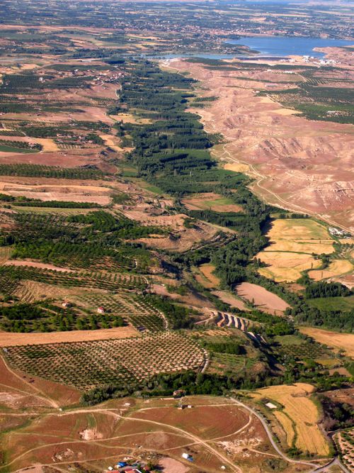 Free Aerial view of farmland with fields, trees, and a distant body of water. Stock Photo
