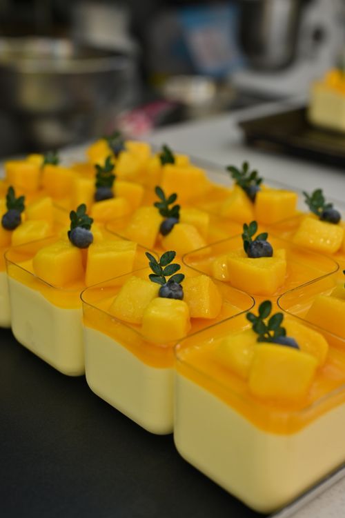 Free Bright mango and blueberry desserts arranged neatly on a kitchen counter, perfect for summer treats. Stock Photo