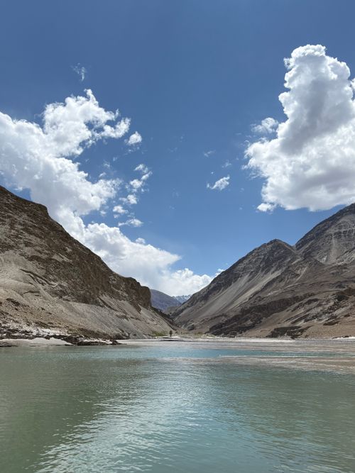 Free A breathtaking view of a river valley in the Himalayas with clear blue skies and dramatic clouds. Stock Photo