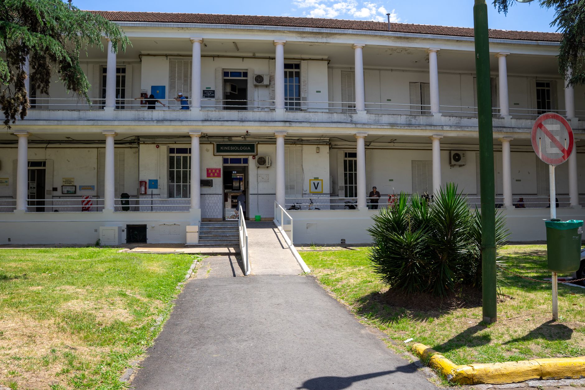 Exterior view of a historic building with columns, surrounded by greenery and a clear sky.