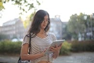 Calm pensive female freelancer using digital tablet on street
