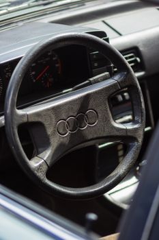 Detailed view of a vintage car's steering wheel and dashboard interior.