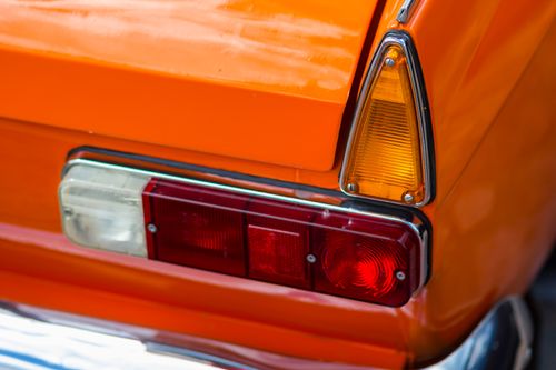 Free Detailed view of an orange vintage car's tail light and fin design, showcasing vibrant 70s automotive style. Stock Photo