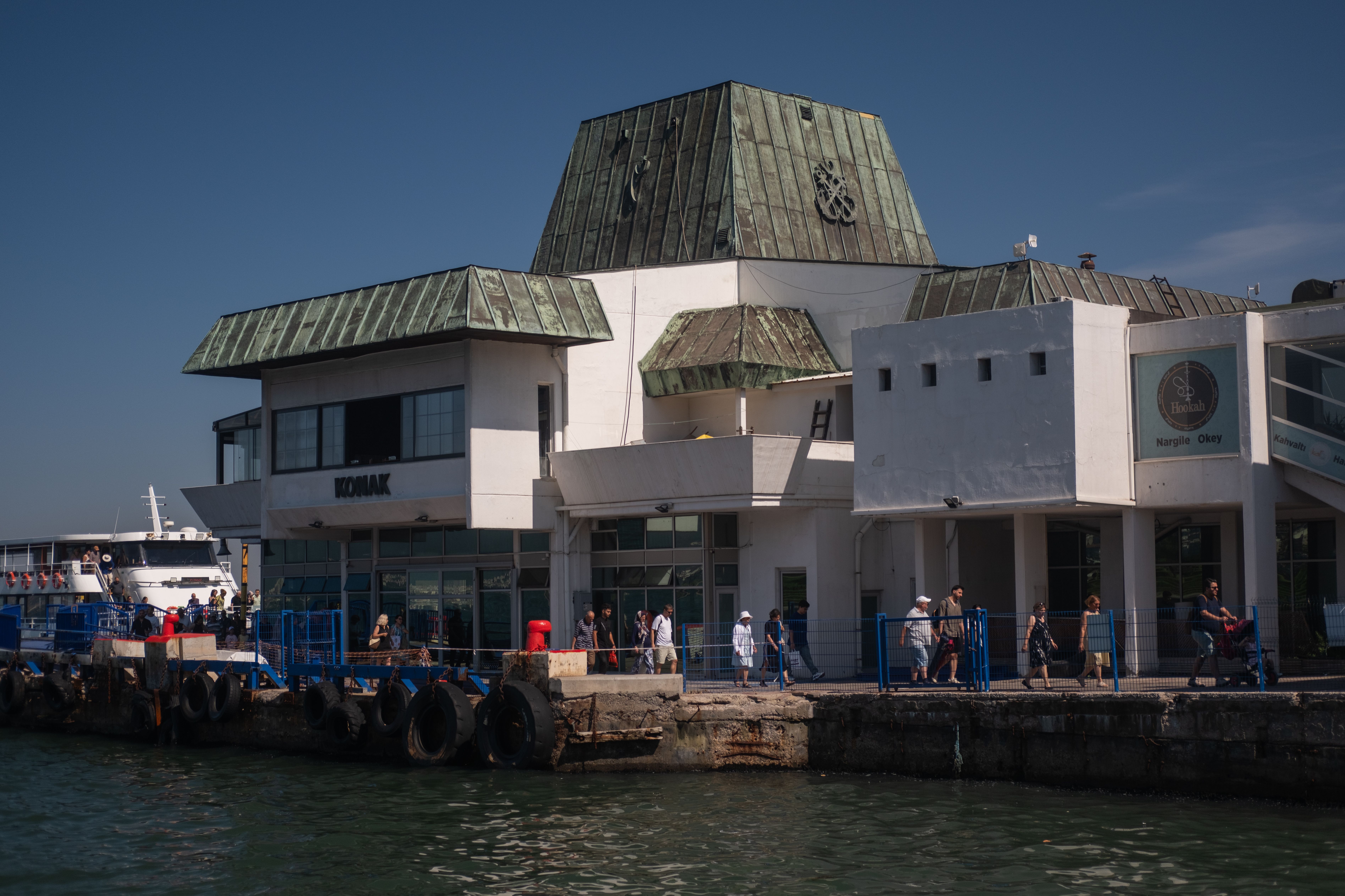 Tourists and locals at the busy Izmir ferry terminal on a sunny day. — Trójmiasto