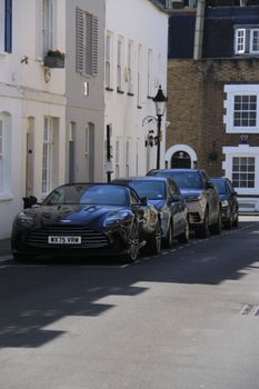 Luxury cars parked in a picturesque urban street on a sunny day.