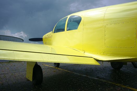 Close-up of a yellow airplane on a runway under a cloudy sky.