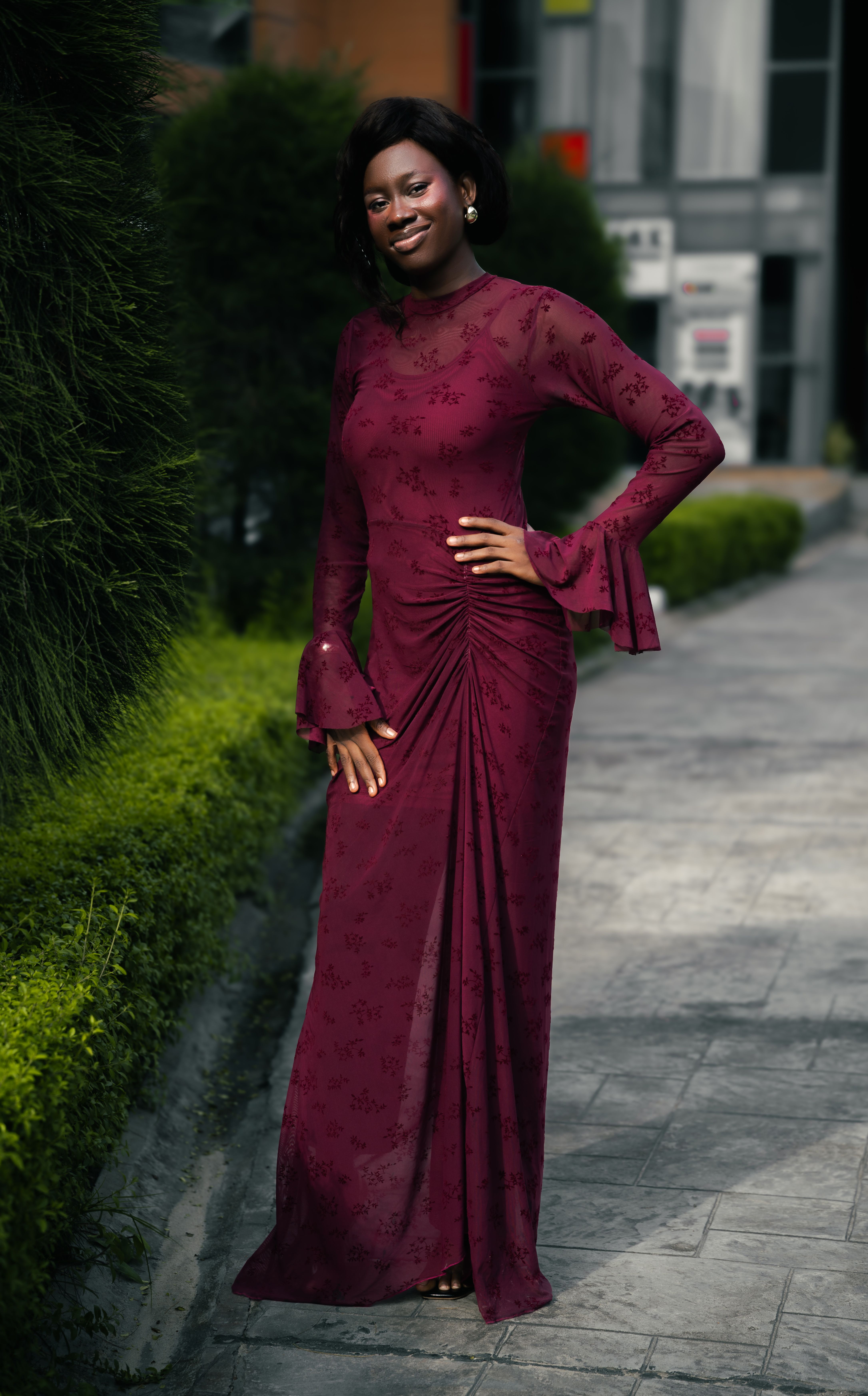 Woman wearing an elegant burgundy wedding guest outfit idea for a fall wedding