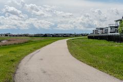 Scenic suburban pathway on a cloudy day, lined with green grass and residential buildings.