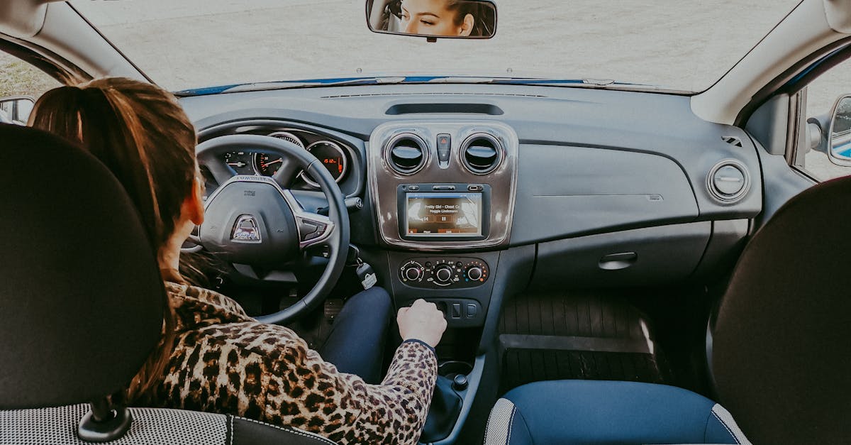 Back view of modern woman in stylish fur coat driving car confidently looking away