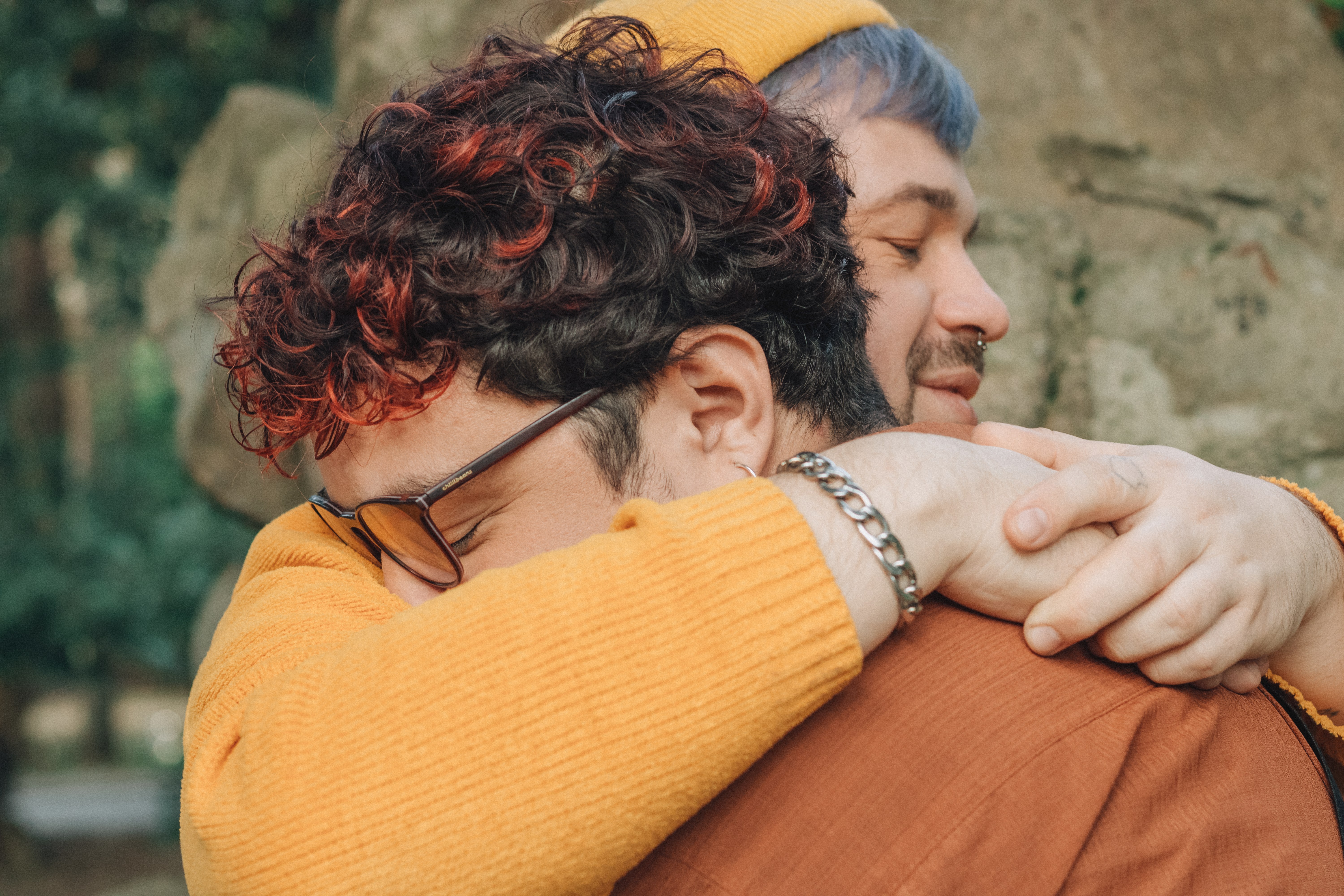 A touching moment of two people embracing outdoors with nature in the background.