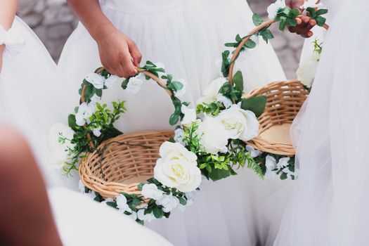 Close-up of flower baskets held by children in wedding attire, showcasing elegance and celebration.