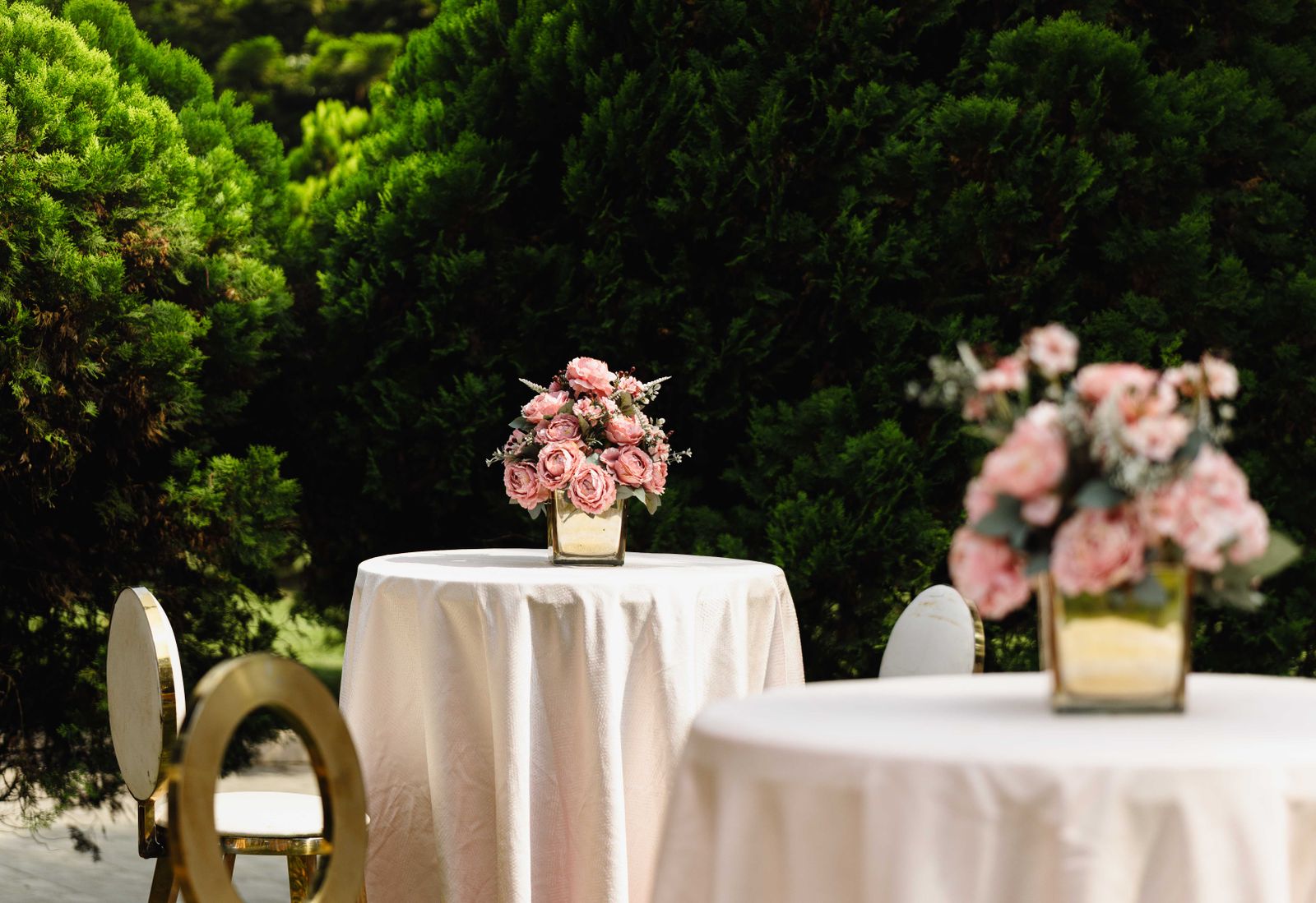 Cocktail tables with soft pink flowers in a green garden