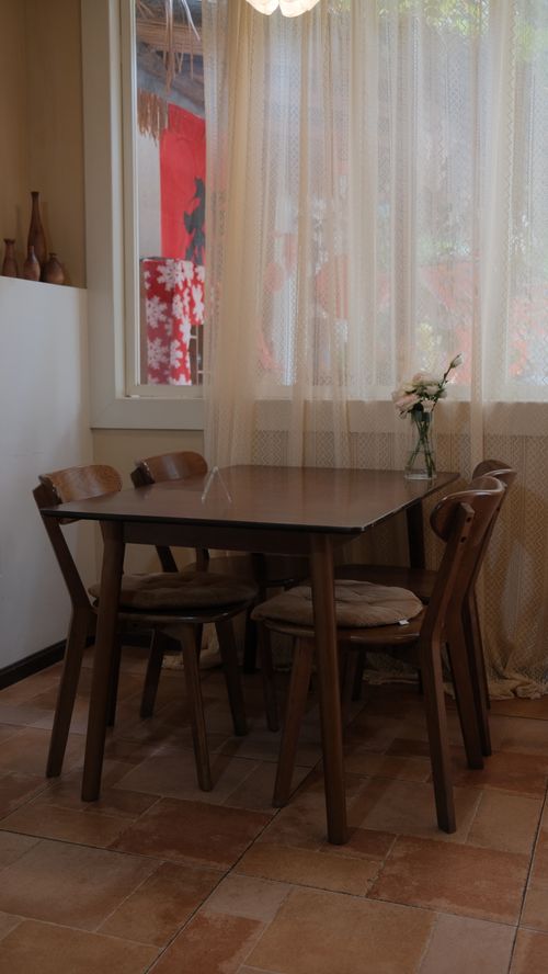 Free A peaceful dining corner with wooden furniture and a floral vase by the window. Stock Photo