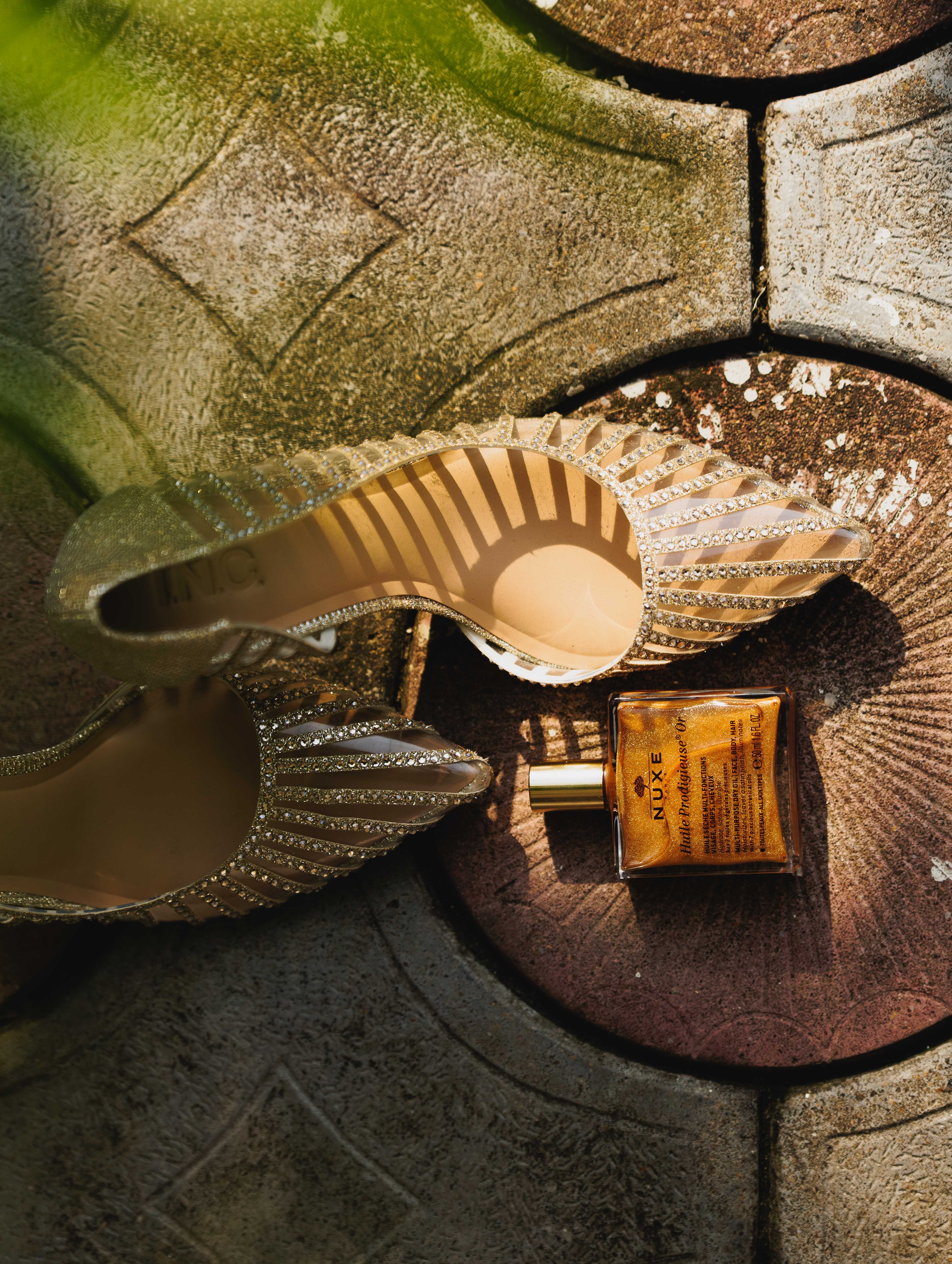 Golden high heels and perfume bottle create a luxurious and stylish atmosphere on a stone surface.