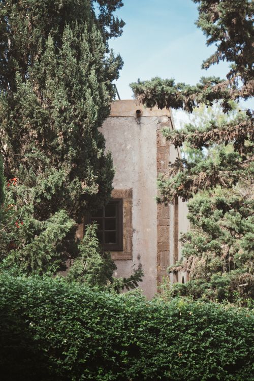 Free Old stone building amidst vibrant green trees under a clear sky. Stock Photo
