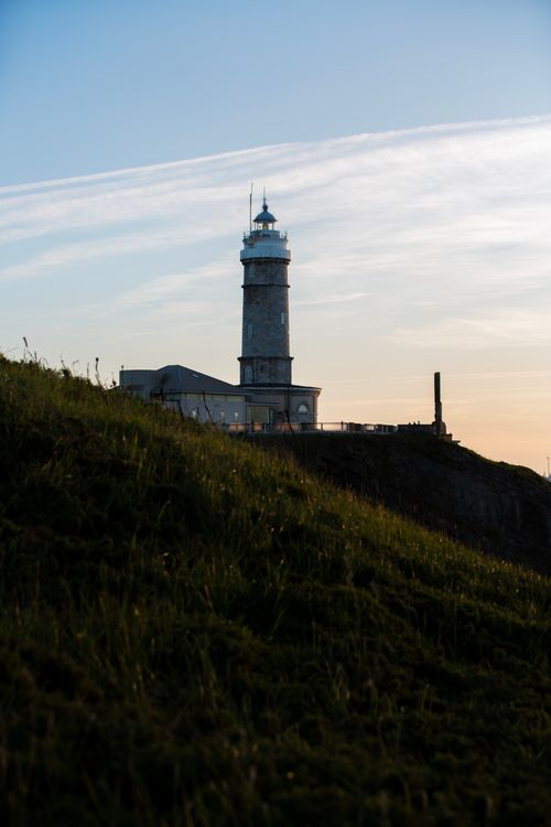 Free Dramatic view of a solitary lighthouse on a coastal cliff at sunset, perfect for travel and landscape themes. Stock Photo