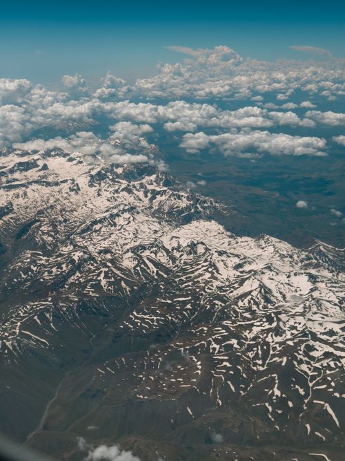 Free Majestic aerial view of a snow-covered mountain range with scattered clouds, showcasing natural beauty. Stock Photo