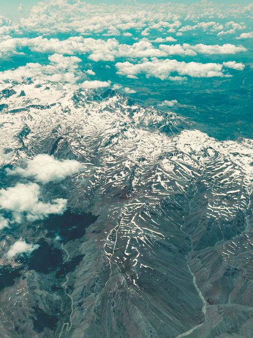 Free A breathtaking aerial shot showcasing a vast snow-covered mountain range under a partly cloudy sky. Stock Photo