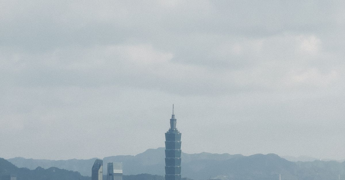 Aerial view of Taipei City showcasing the iconic Taipei 101 skyscraper against a mountainous backdrop.