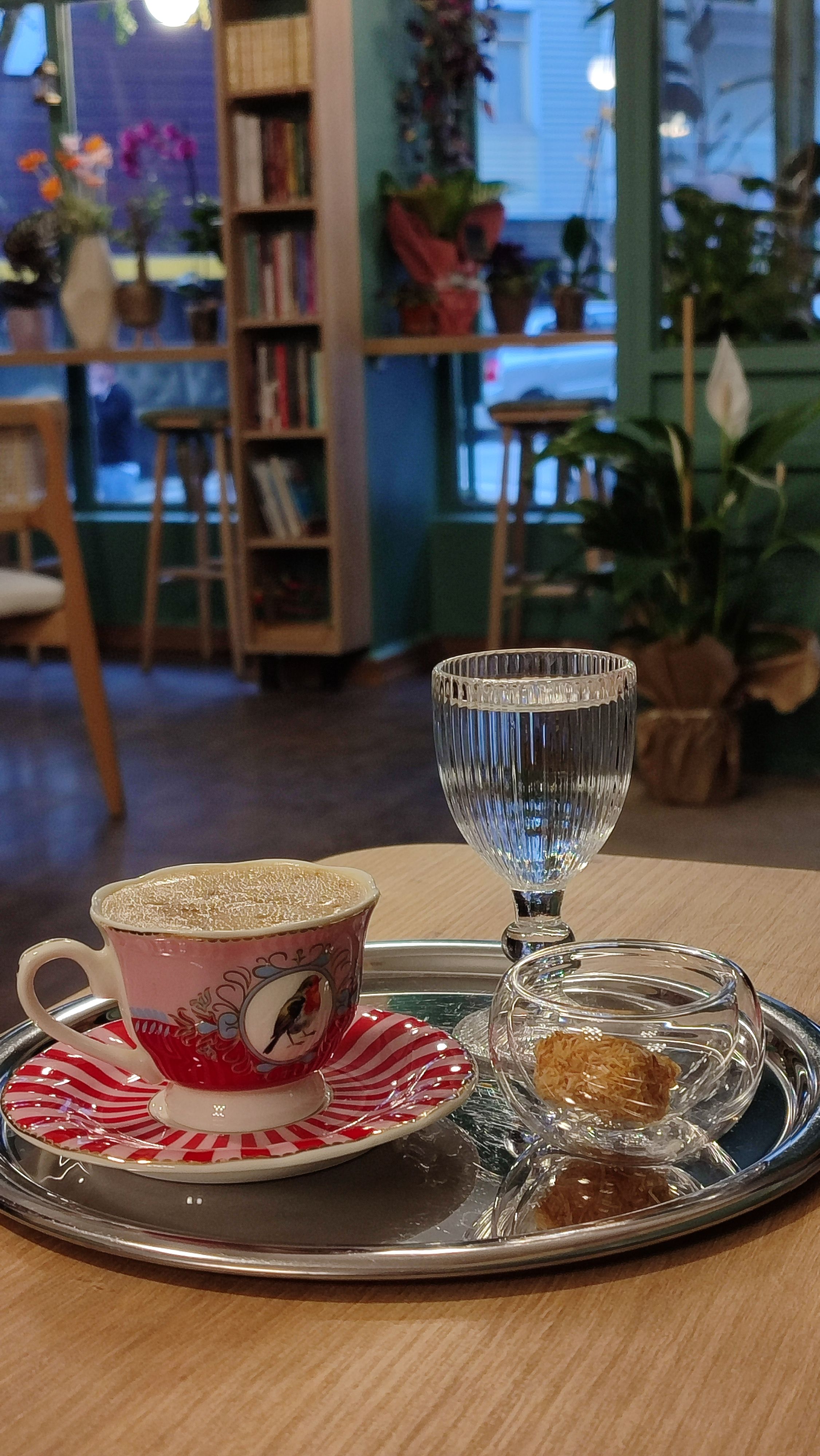 A warm café scene featuring coffee, a glass, and a pastry on a tray.