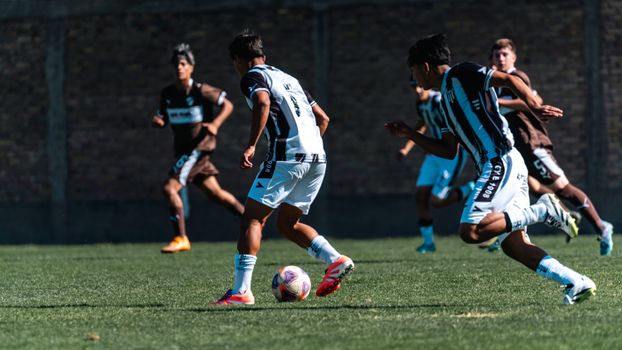 Teenage boys play competitive soccer on a sunny day, showcasing teamwork and agility.