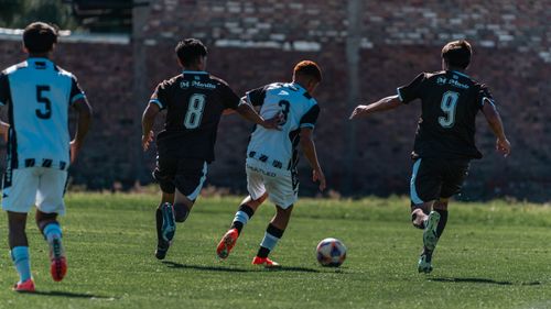 Free Four players engage in a competitive outdoor soccer match on a sunny day. Stock Photo