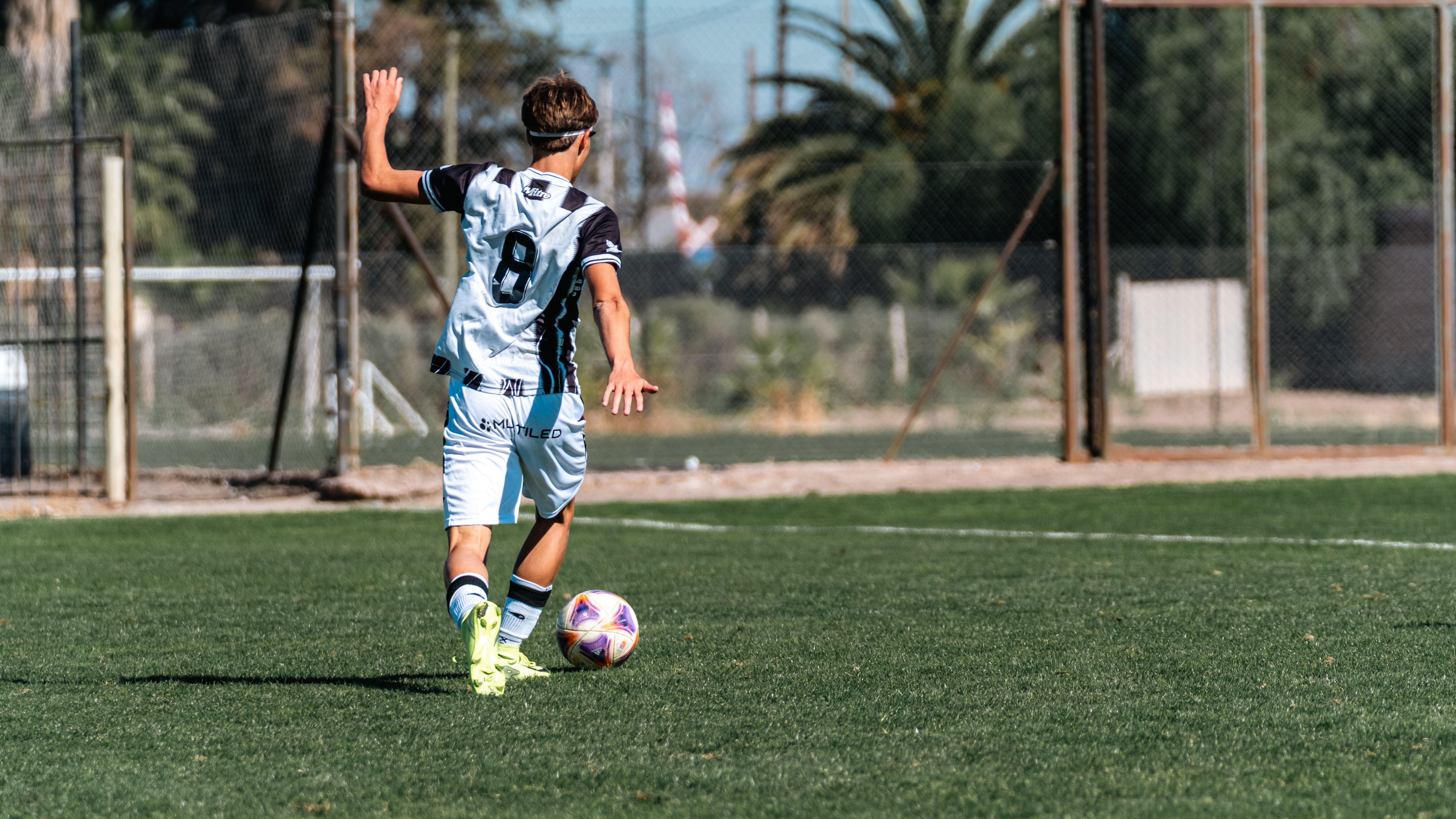 A young soccer player with jersey number 9 dribbles a ball on a sunny day outdoors.