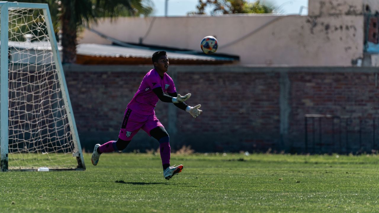 action shot of a goalkeeper in a pink uniform throwing a soccer ball o