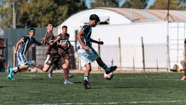 Teenagers playing an intense soccer match on a sunny day, showcasing teamwork and competition on the field.