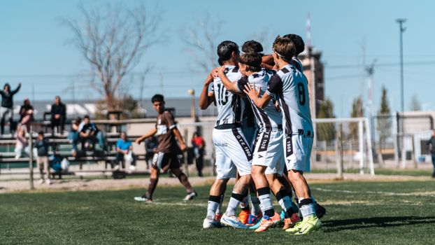 A youth soccer team in white jerseys celebrates a win on a sunny day.