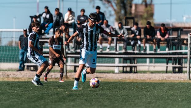 Dynamic action shot of teenage soccer players competing outdoors during a daytime match.