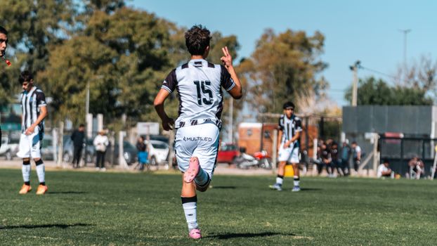 Young soccer player celebrates during a match on a sunny day outdoors.