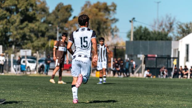 Back view of a soccer player with jersey number 15 running on a green field during a match.