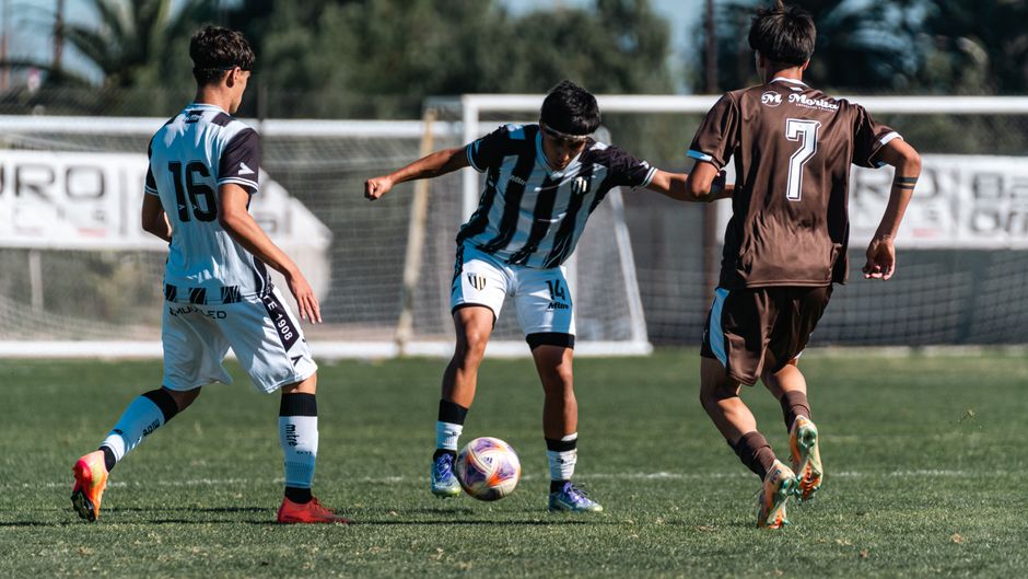 Three young soccer players in action on a sunny field during a match.