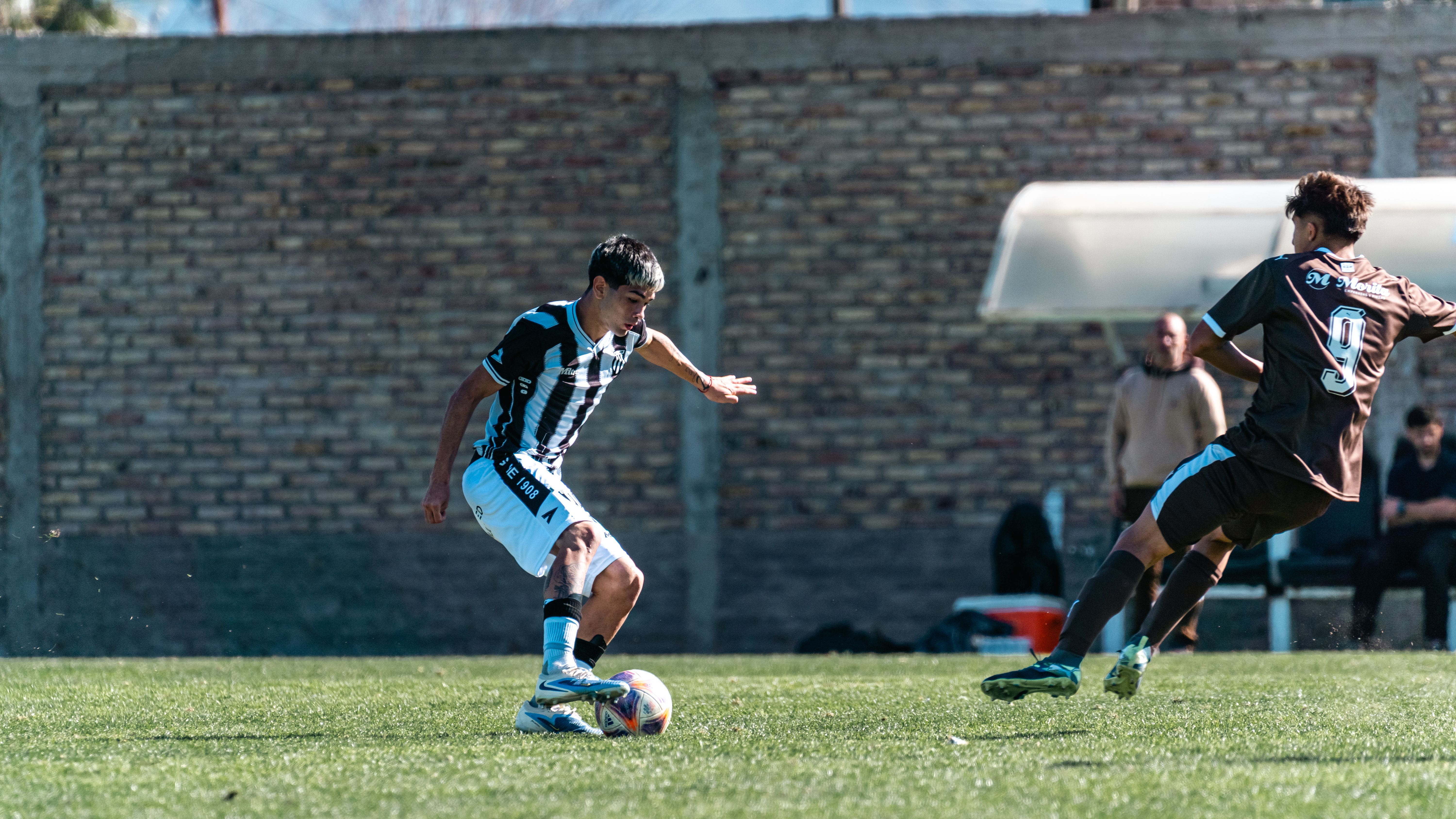 Two male soccer players competing during a daytime match on a grassy field.