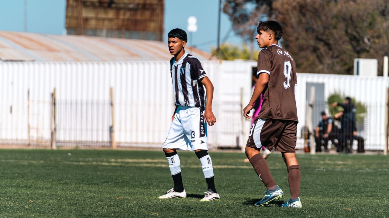 two teenage soccer players in action on an outdoor field during a sunn