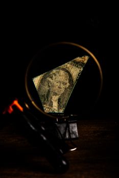 Close-up of a magnified torn dollar bill fragment on a dark background.