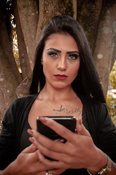 Portrait of a stylish young woman browsing her smartphone in a tranquil forest setting.