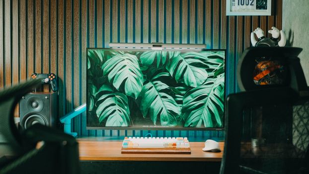 Modern home office with a stylish desk setup, featuring a monitor displaying green foliage.
