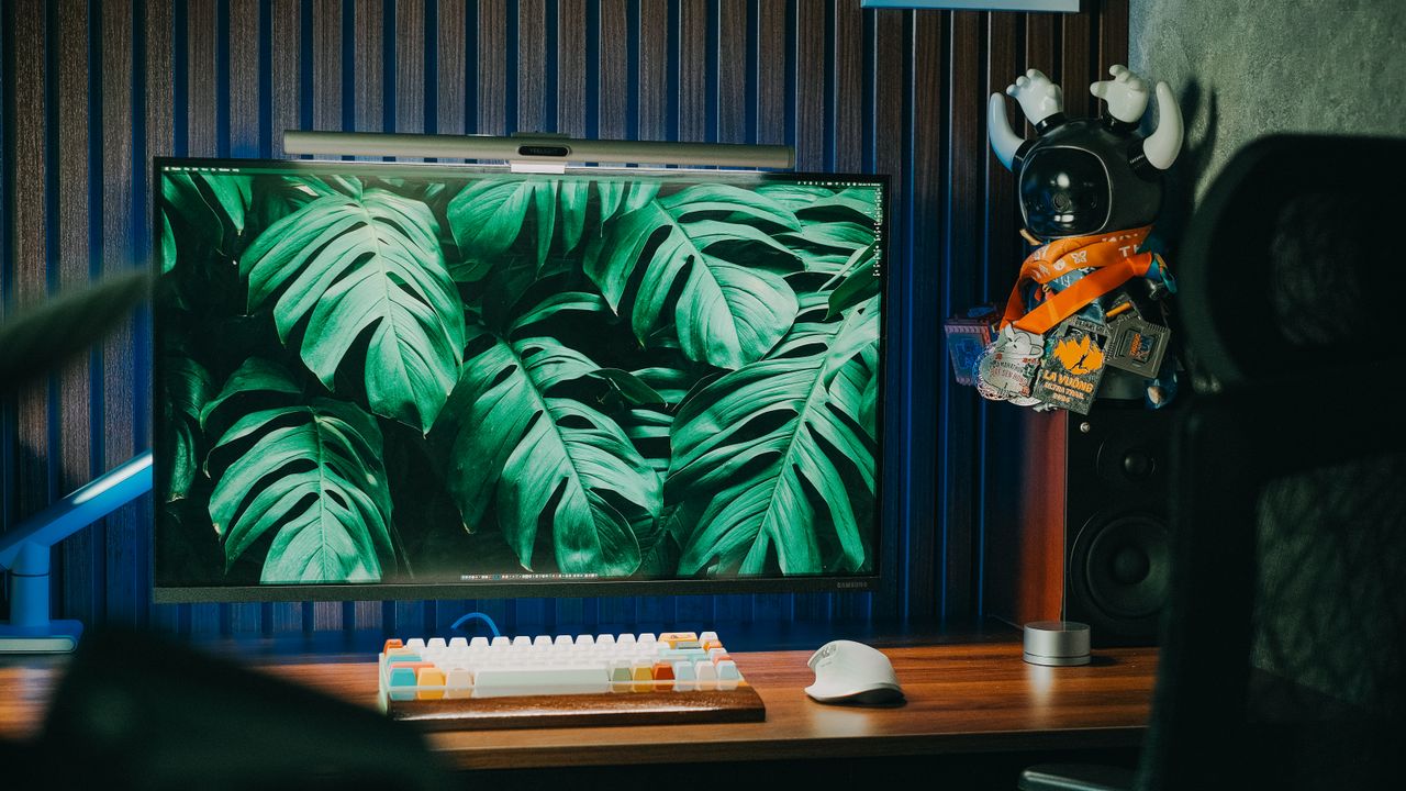 a modern home office setup with a pc keyboard and monstera leaves wall